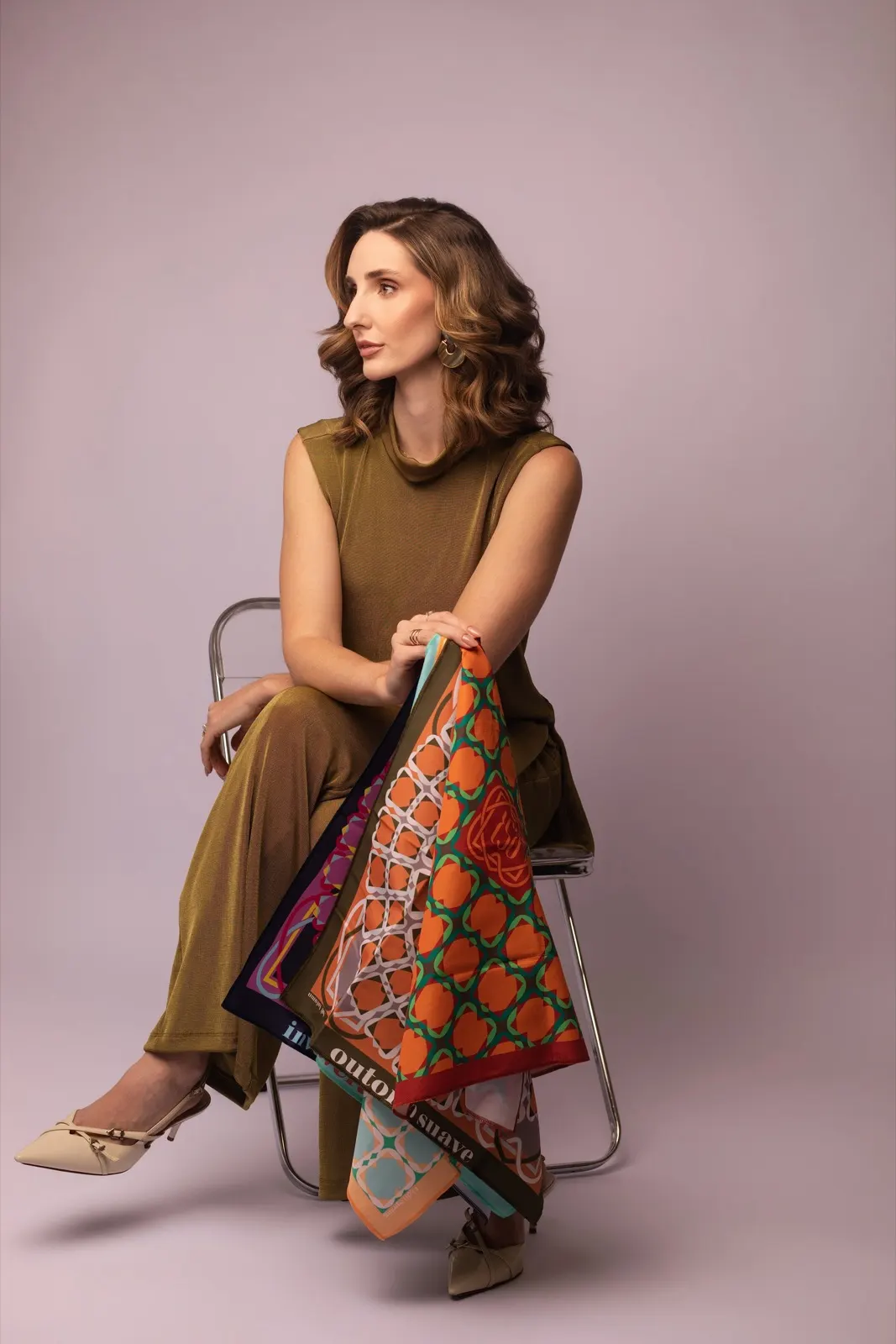 Iôlany sentada em uma cadeira, com lenços coloridos no colo